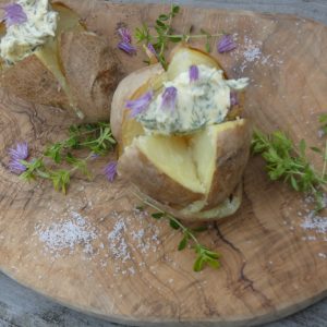Gepofte aardappel met kruidenboter baked potatoes with butter on a wooden board